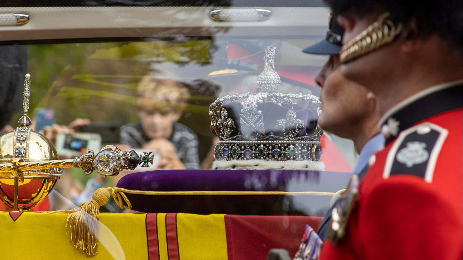 Boy watching queens the queens coffin with crown and sceptre.